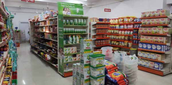 (Dukan Ke Racks) kirana store rack in Bhopal, Madhya Pradesh. Racks Manufactured by GKSP RACKING. It shows multiple aisles and sections. There are signs visible for different product categories like "DIAPERS/PADS" and "HEALTH & BEAUTY". The central area shows more Ariel detergent boxes and plastic containers. The overall impression is of a well-stocked, organized, and modern grocery store or supermarket.