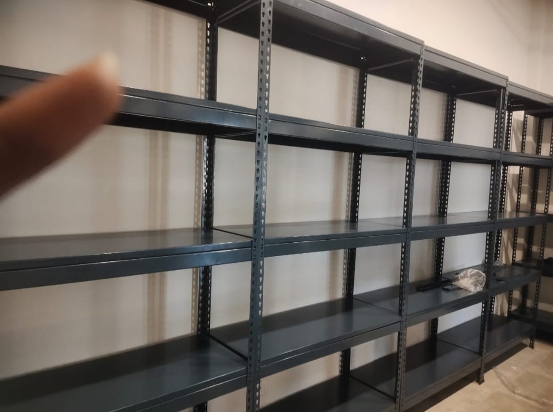 boltless rack of dark grey color installed at an office for storage purpose. 36 inches width, 15 inches depth, 5 shelves and 6feet height. wall is white in color.